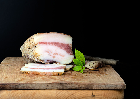 close-up of italian guanciale or pancetta on wooden cutting board